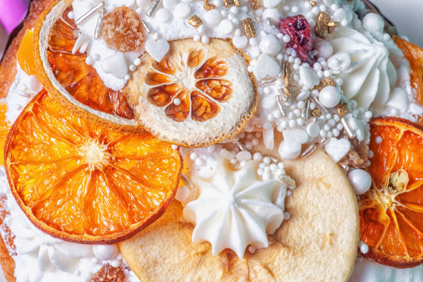 复活节蛋糕装饰特写。水果蛋糕装饰干橘子片，梨，白色蛋白酥皮，糖霜，糖屑。装饰kulich的细节，俯视图图片下载