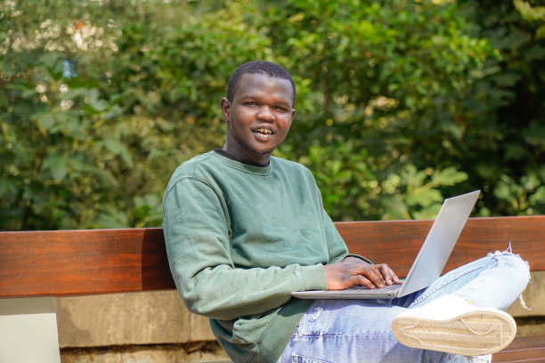 来自非洲的男孩用电脑看着相机工作。黑人图片下载