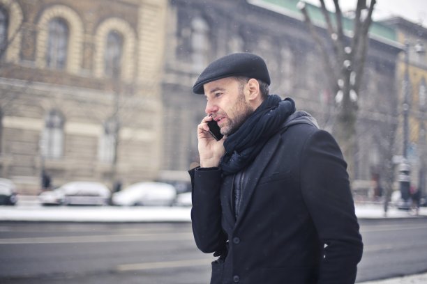 帅气的意大利男人戴着围巾，穿着外套站在外面的街道上打电话图片下载