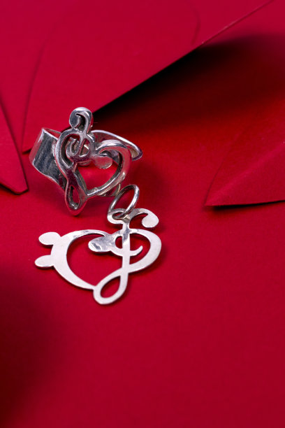 情人节背景。垂直照片的爱戒指与吊坠和红色爱心的背景。图片下载