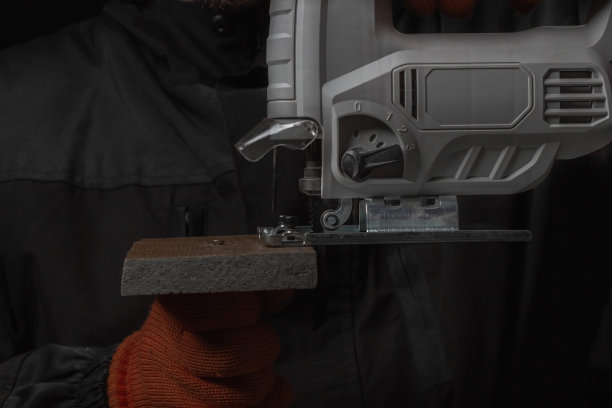 电动拼图，在妈妈的手锯木材隔离在黑色背景图片下载