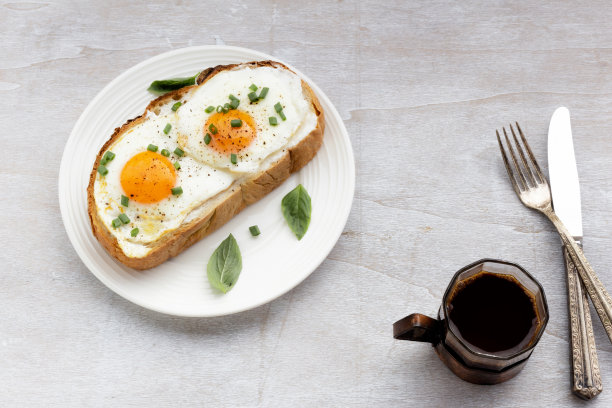 早餐是煎蛋，面包片放在盘子里，咖啡放在白木桌上图片下载