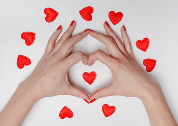 女性手指呈心形围绕着一颗小红心。情人节。图片下载