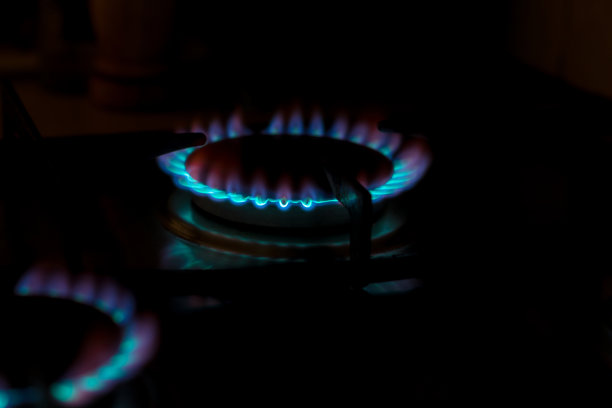 近距离拍摄的蓝色火焰从家庭厨房灶台顶部。燃烧着丙烷气体的煤气灶。能源的概念图片下载