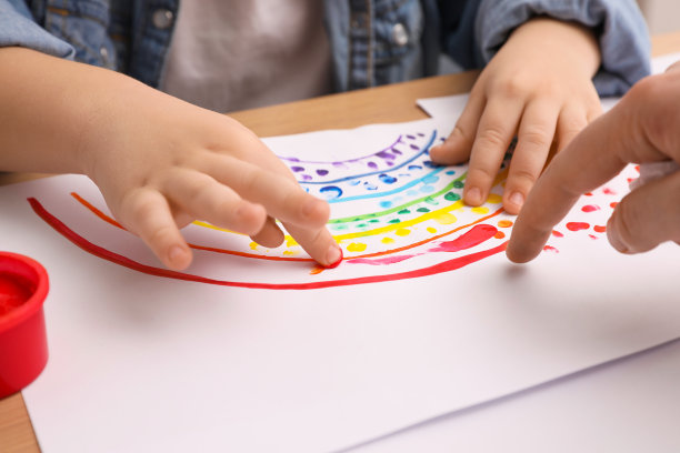 小男孩在室内木桌上用手指画画，特写图片下载