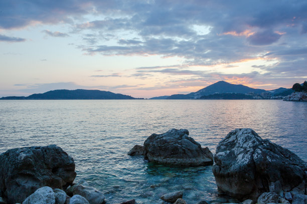 日落时的海景和石头海滩。岩石海岸线与岛屿在天际线上的出版物，海报，日历，帖子，屏幕保护程序，壁纸，明信片，横幅，封面，网站。高质量照片图片下载