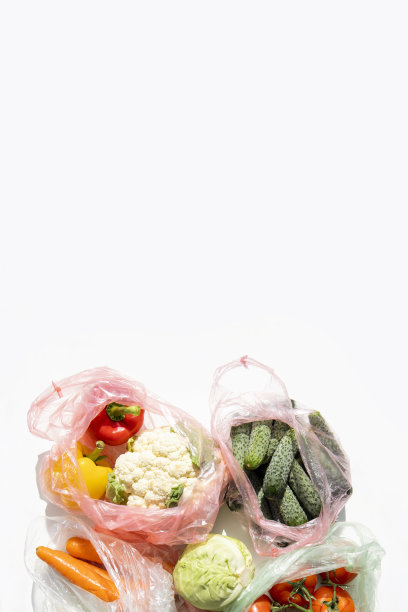 新鲜蔬菜装在塑料袋里，放在白色的桌子上。俯视图，平面布局图片下载
