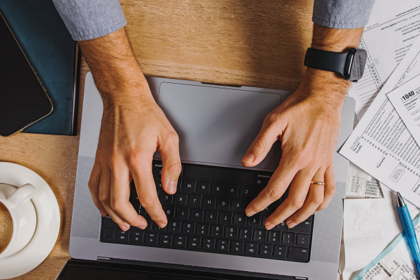 男子在笔记本电脑上打字，填税的俯视图图片下载