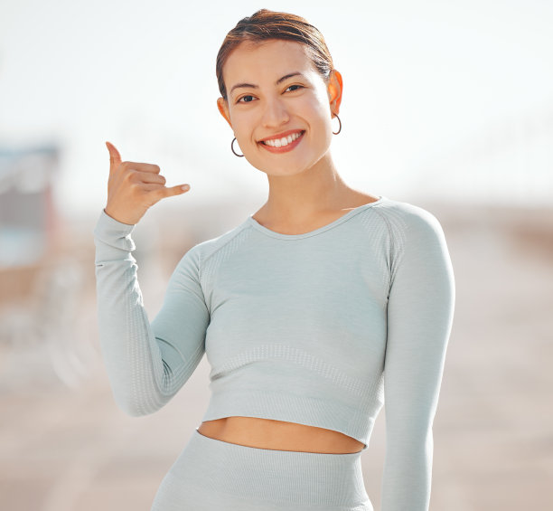 女性，在夏威夷的肖像和冲浪者手势或调情，在户外运动休息时打电话给我。来自流行文化的快乐、友好和欢迎的手势符号，用于年轻人的问候。图片下载