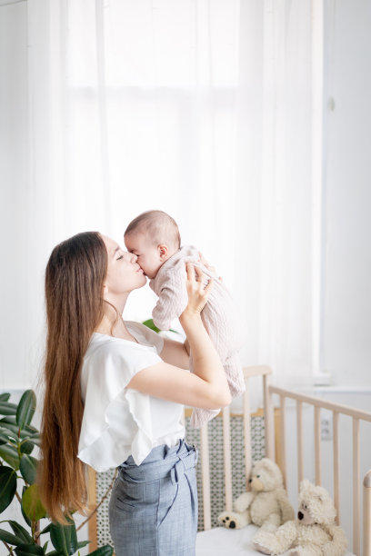 年轻的母亲在卧室里抱着她的女婴亲吻图片下载