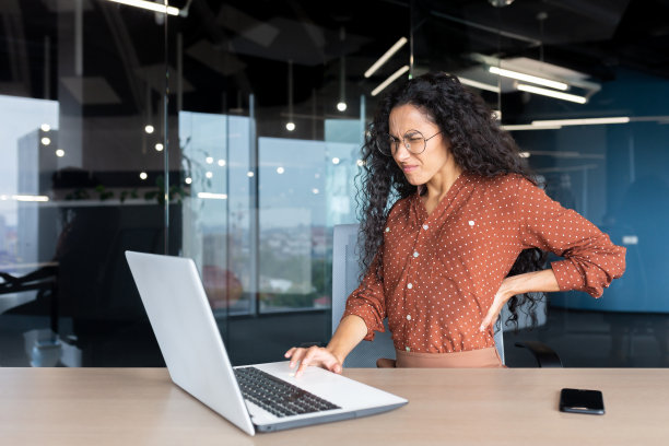 过度疲劳的西班牙裔女性工作到很晚，女商人背痛，女工在办公室里坐在桌旁使用笔记本电脑工作图片下载