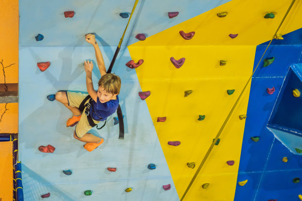 一个6岁的孩子在攀岩中心的墙上攀岩图片下载