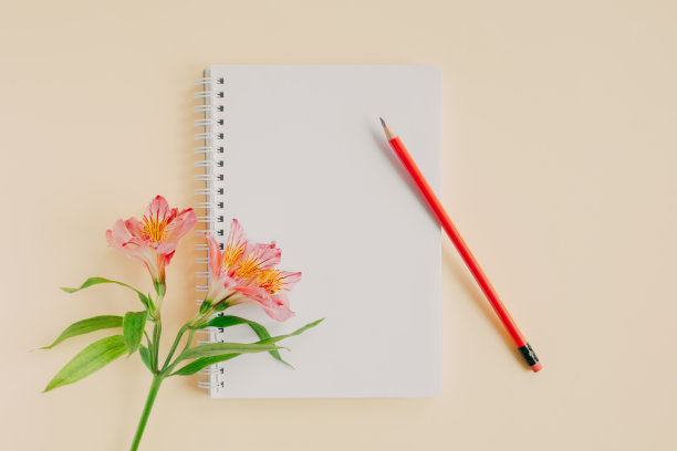 笔记本空白页，粉红色的花和铅笔在淡黄色的背景。图片下载