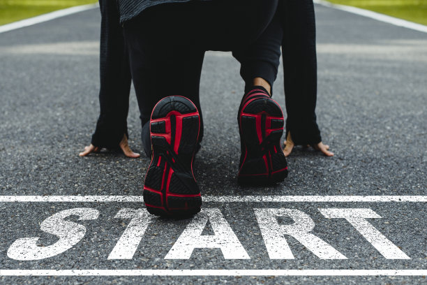 柏油路上写着“开始”字，运动员在路上准备起跑。挑战或职业道路和改变的概念。图片下载