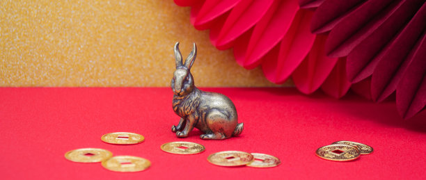 横幅上有一个青铜形象的兔子与金币-象征中国新年2023金和红色的背景，复制空间图片下载