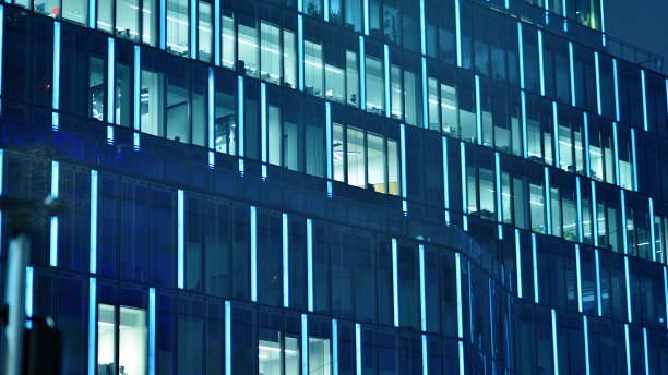 图案的办公楼窗户在夜间照明。图片下载