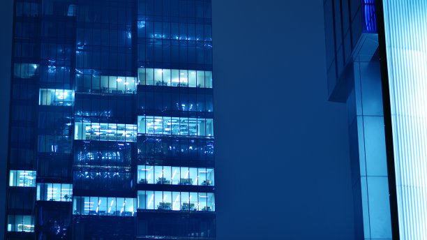 图案的办公楼窗户在夜间照明。图片下载