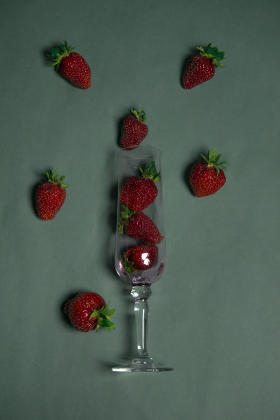 草莓饮料原料的创意安排。多汁的浆果落在一个美丽的水晶杯中，在绿色的背景上。夏日聚会时喝的饮料。作者食谱的概念。图片下载