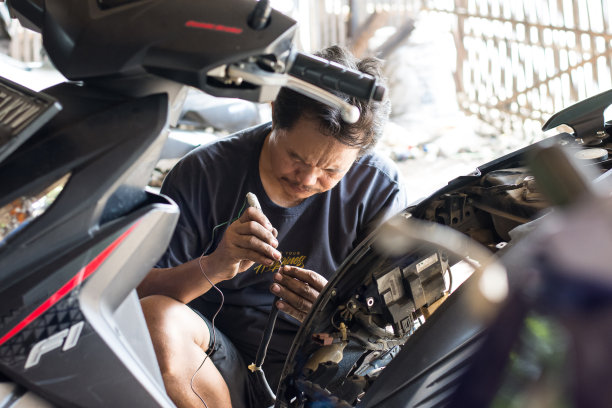 亚洲男性在自己的车间修理摩托车电图片下载