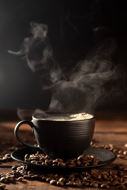 黑色的咖啡杯配上热咖啡和烟雾，覆盖着质朴的木头，深色的美食风格照片，选择性聚焦。图片下载