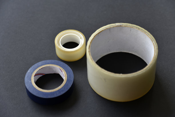 黑色背景上的卷胶带和管道胶带。施工胶带特写。图片下载