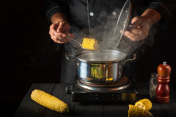 专业厨师煮玉米。特写镜头是厨师在餐厅厨房做饭时的手。免费广告位。图片下载