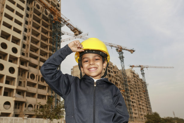 聪明的小学生戴着安全帽站在工地附近图片下载