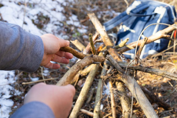 近距离照片的女性手使用干棒篝火户外在冬季阳光明媚的一天，冬季徒步旅行的主题。图片下载