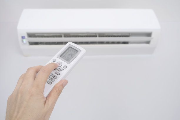 男人的手用遥控器打开他卧室的空调被冷却到25摄氏度。健康概念和节能图片下载