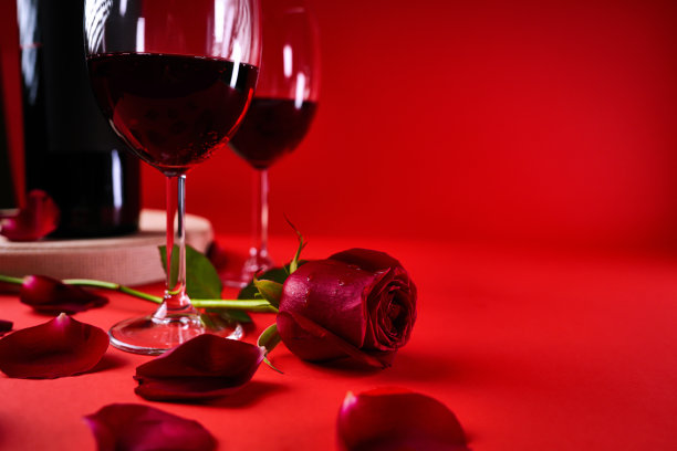 情人节:一瓶红酒，眼镜，红玫瑰，心形盒子和红色背景图片下载