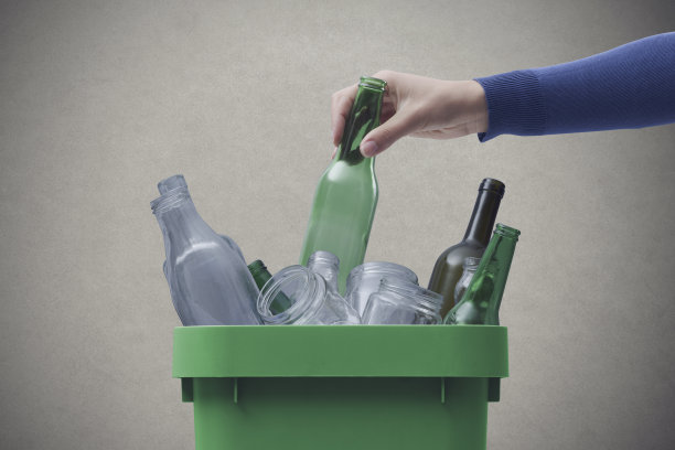 一个女人把一个玻璃瓶扔进垃圾桶图片下载