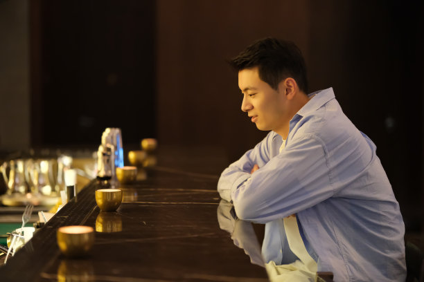 孤独英俊的亚洲年轻男子坐在晚上的酒吧图片下载