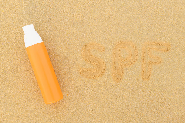 橙色瓶子里的防晒喷雾和沙子上的SPF字样图片下载