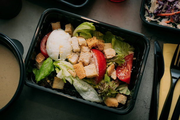准备好健康食品餐饮菜单在饭盒鱼和蔬菜包装作为日常膳食饮食计划快递与叉子隔离在黑色桌子背景。拿走集装箱的顺序概念。图片下载