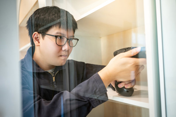 亚洲男性家具装配工使用电钻螺丝刀图片下载