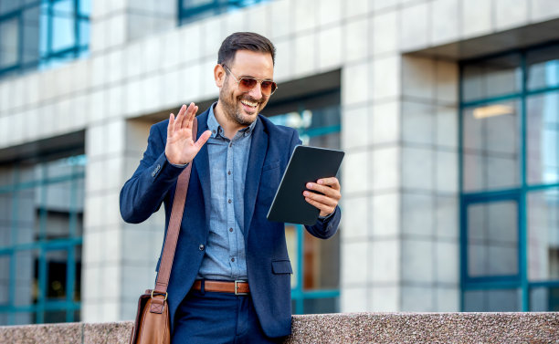 快乐的微笑商人与他的客户通过平板电脑视频通话。商业、生活方式概念图片下载