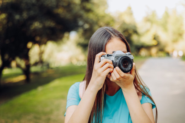年轻女子在公园外用老式胶卷相机拍照图片下载
