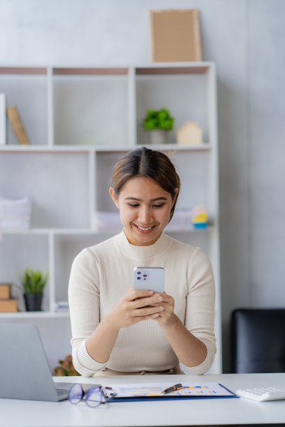 快乐的亚洲女性员工在现代大型办公公司工作经理专业商人或员工使用笔记本电脑打电话。垂直的图像图片下载