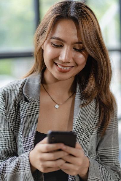 快乐的亚洲女性员工在现代大型办公公司工作经理专业商人或员工使用笔记本电脑打电话。垂直的图像图片下载