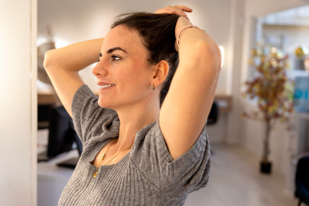 自信的年轻女子抓住她的头发与她的手投射出一个美好的微笑图片下载