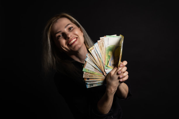 快乐的女商人拿着欧元钞票，孤立在黑色背景上图片下载