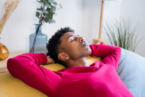 梦幻的黑人男人闭着眼睛睡在家里的沙发上图片下载