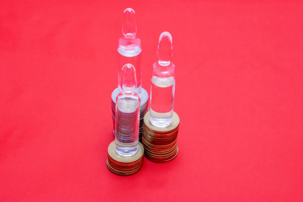 硬币上的红色背景是装有药物的透明小瓶。药品成本的说明。用于演示、广告。图片下载