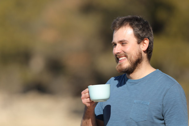 快乐的男人手拿咖啡杯欣赏自然风光图片下载