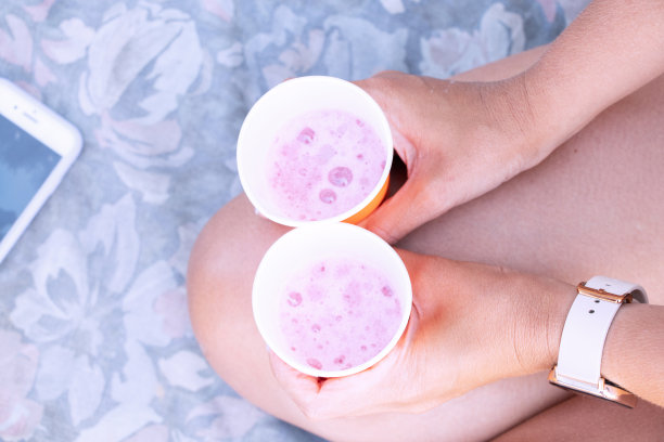 这个女孩手里拿着两个一次性玻璃杯，里面装着度假时在海滩上玩的酒，杯子里装着香槟图片下载