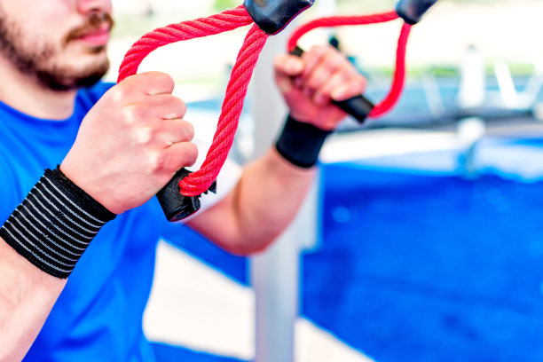 近距离的男性手在锻炼与悬挂带在健美操公园图片下载