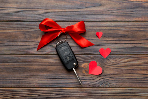 彩色桌子上有红色蝴蝶结和心形的车钥匙。赠送情人节或圣诞节礼物，顶视图与复制空间图片下载