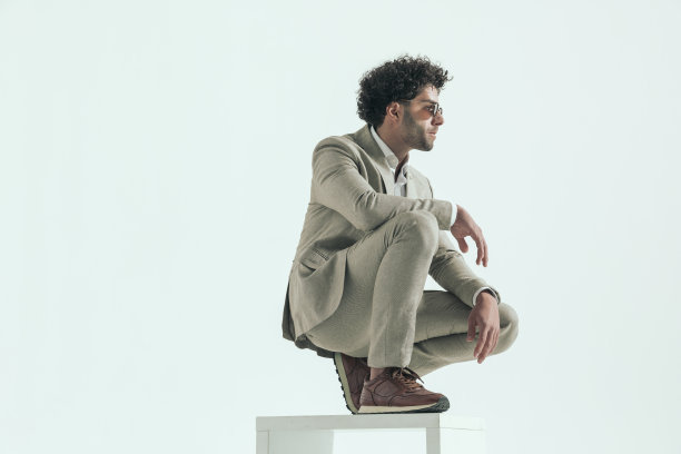 有着卷发的年轻男人蹲着看向侧面图片下载