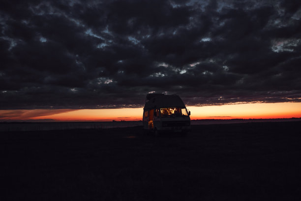 露营车剪影在自然湖附近日落。图片下载