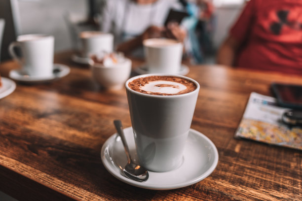白色的咖啡杯放在木桌上，人们在享受。咖啡的艺术图片下载
